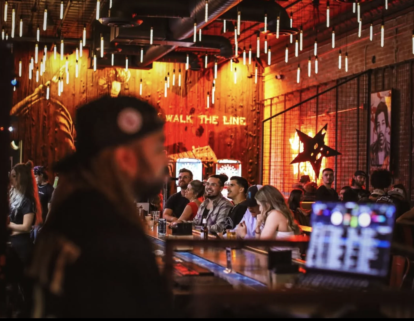 A lively crowd beneath pendant lights at Rebel & Rogue